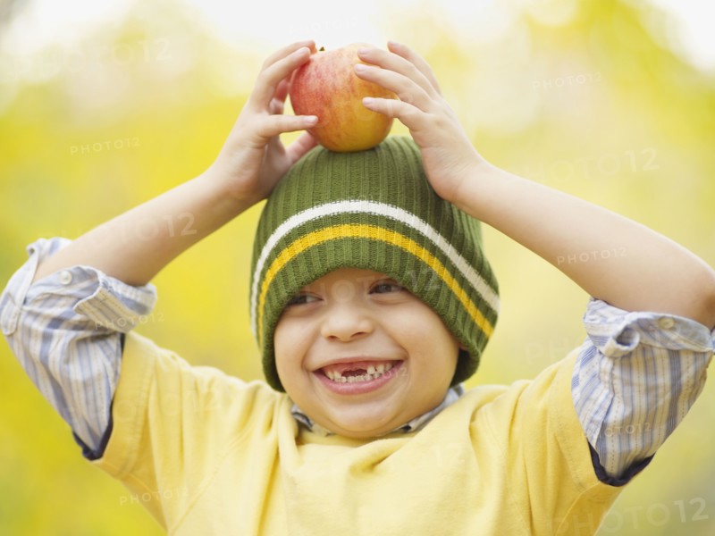 Toothless Hispanic boy balancing apple on head
