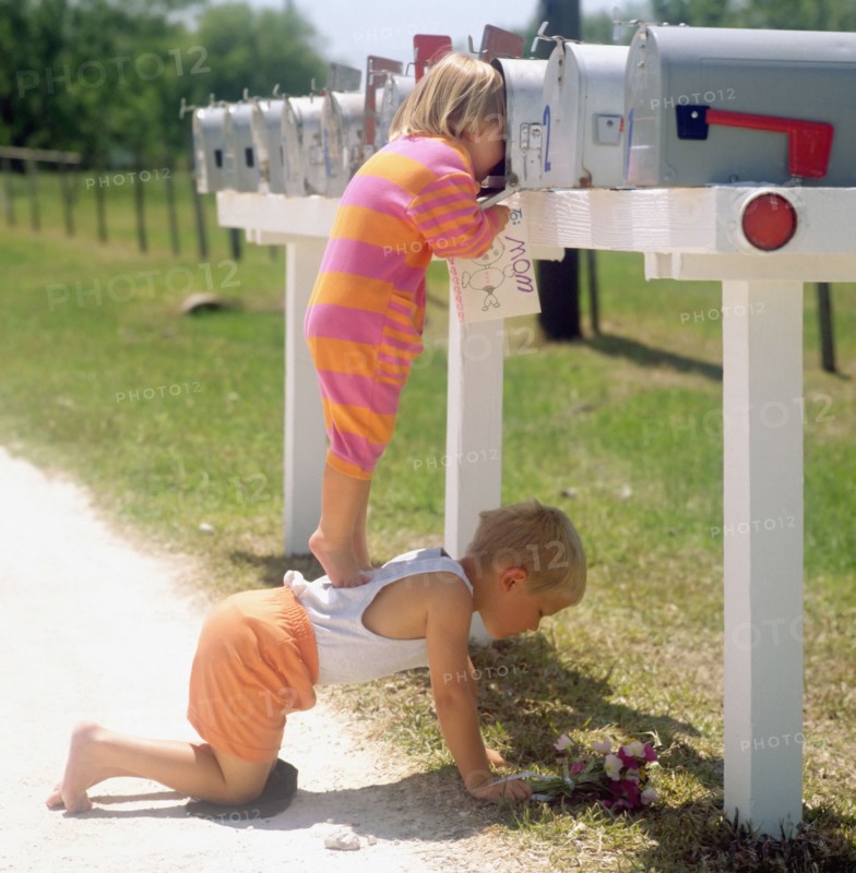 Girl standing on brother's back and peering into mailbox