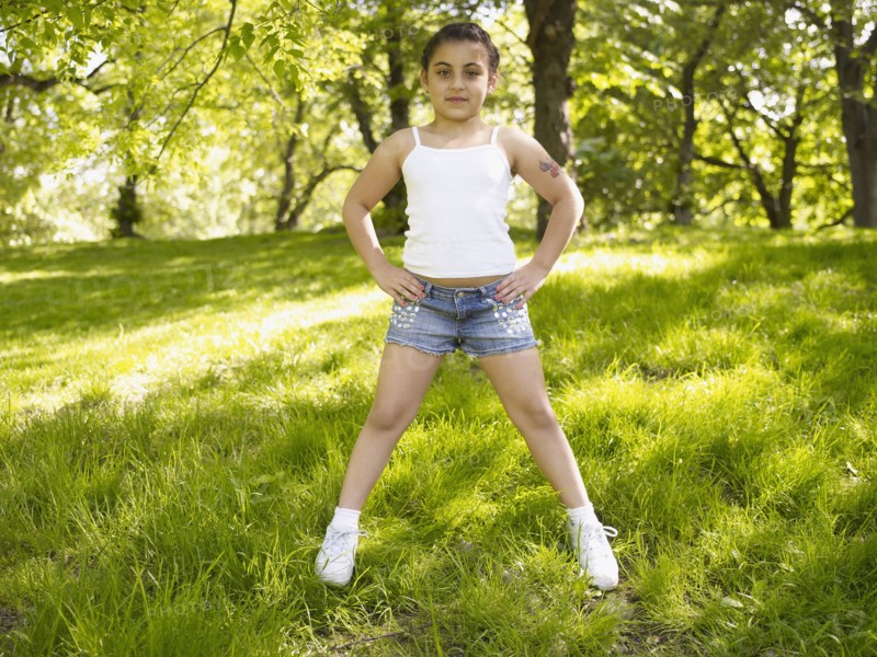 Mixed race girl with hands on hips in grass