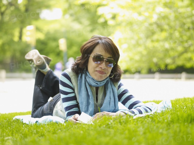 Hispanic woman laying on blanket in grass