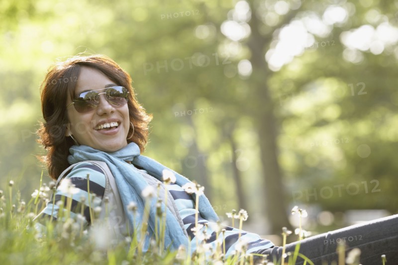 Smiling Hispanic woman laying in grass