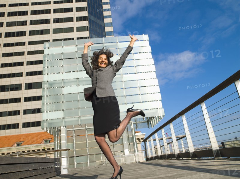 Excited Caucasian Businesswoman standing on one leg in city