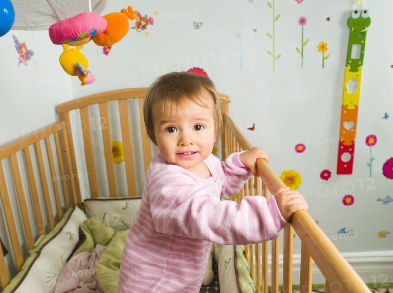 Mixed race baby girl standing in crib