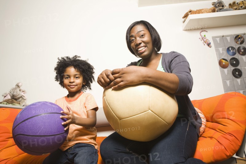 African American mother and son holding balls