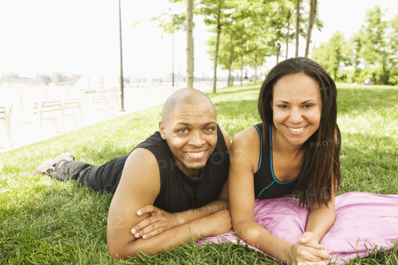 Smiling couple laying in grass at park