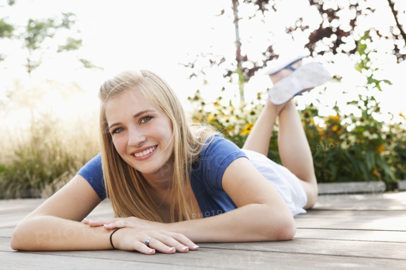 Smiling Caucasian teenager laying on deck