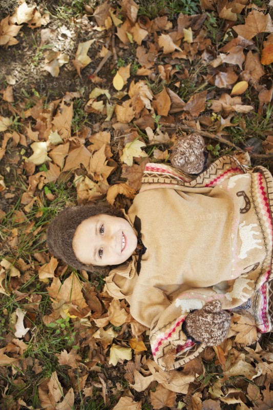 Mixed race girl laying in autumn leaves