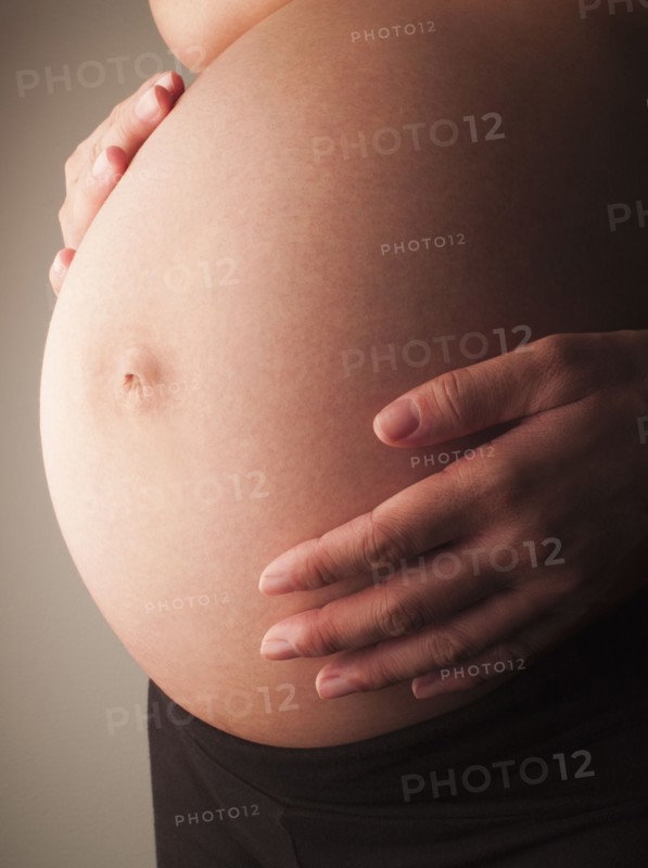 Mixed race woman holding pregnant stomach