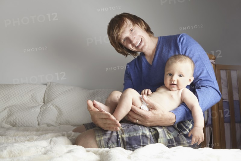 Father holding baby on bed