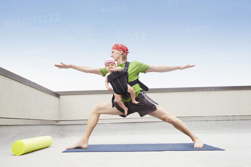 Father practicing yoga and holding baby