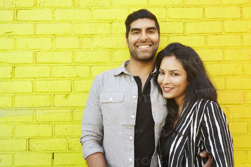 Indian couple hugging in front of yellow brick wall