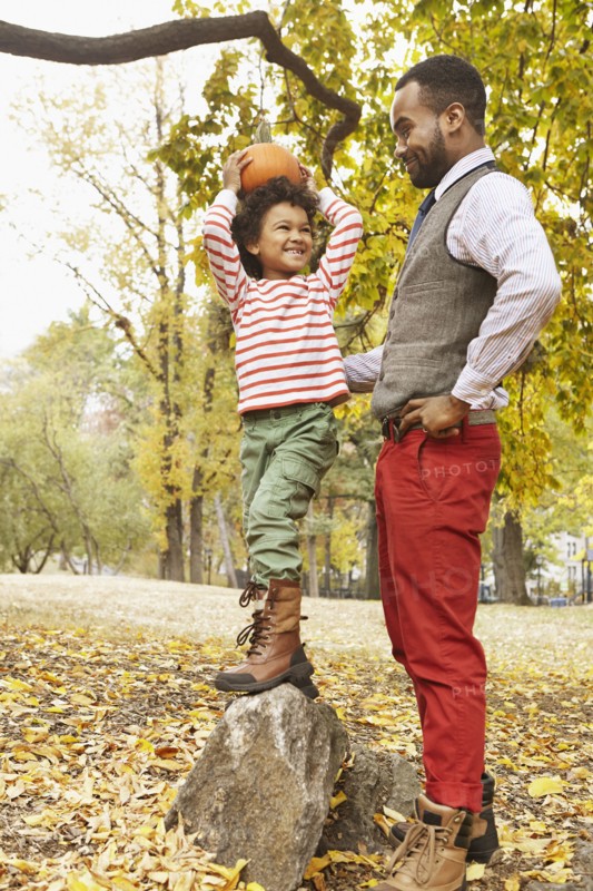 Father and son holding pumpkin in park