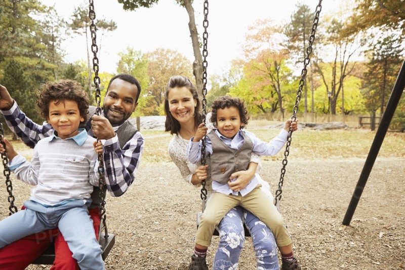 Family sitting on swings in park