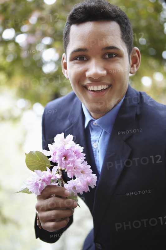 Smiling man in suit holding flower