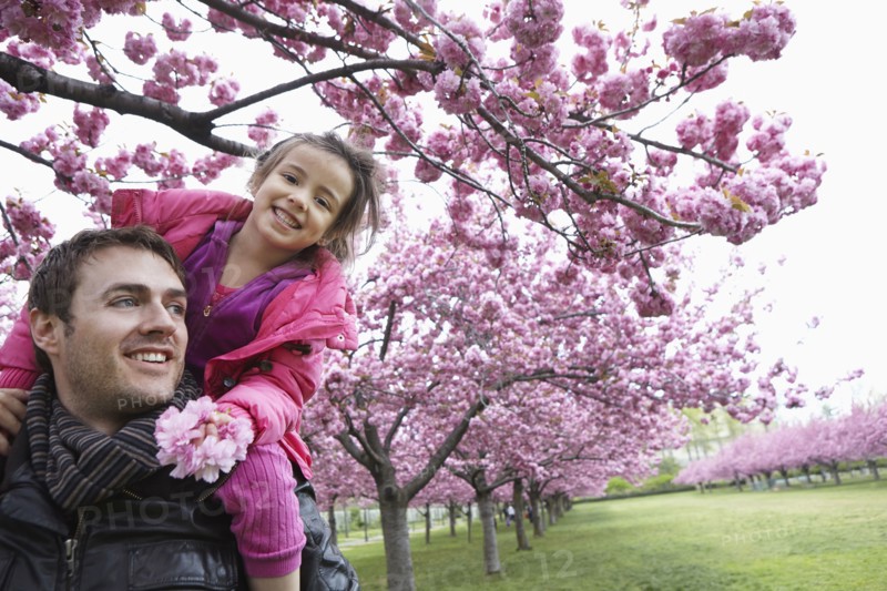 Father carrying daughter on shoulders in park