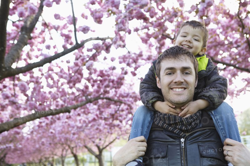 Father carrying son on shoulders in park