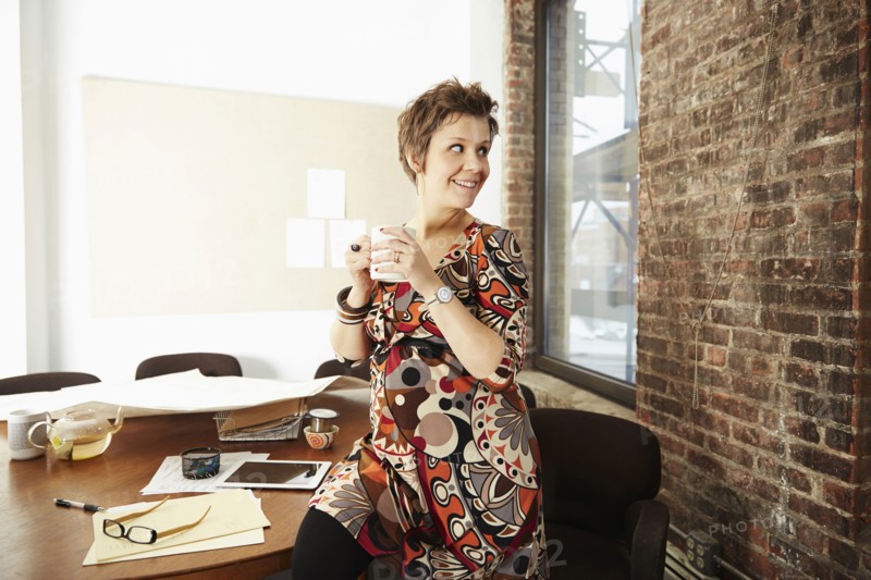 Pregnant businesswoman drinking coffee in office