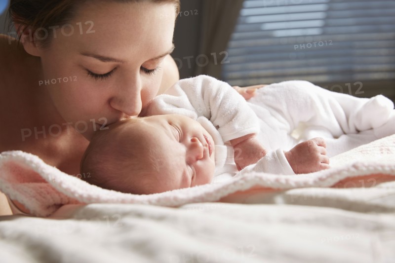 Mother kissing newborn baby on blanket