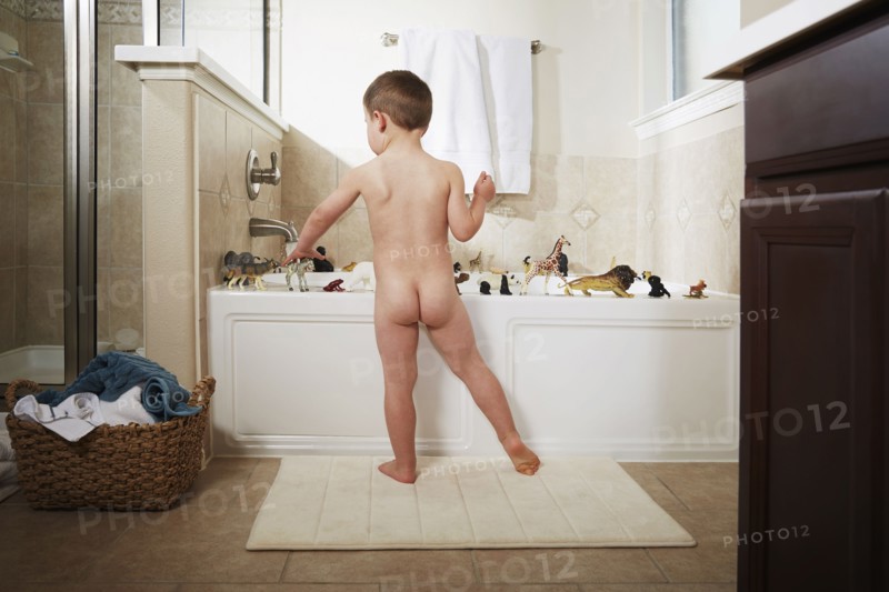 Nude Caucasian boy playing in bathtub
