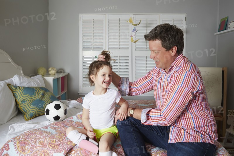 Caucasian father holding hair of daughter