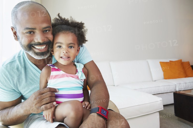 Black father and daughter sitting in living room