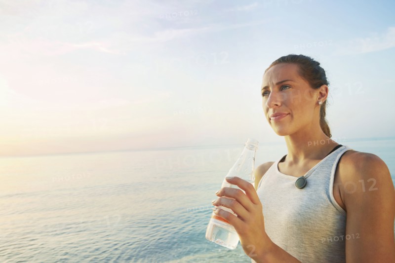 Athlete drinking water bottle on beach