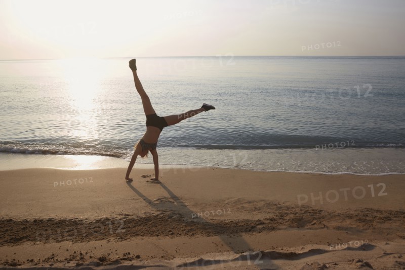 Athlete doing cartwheel on beach