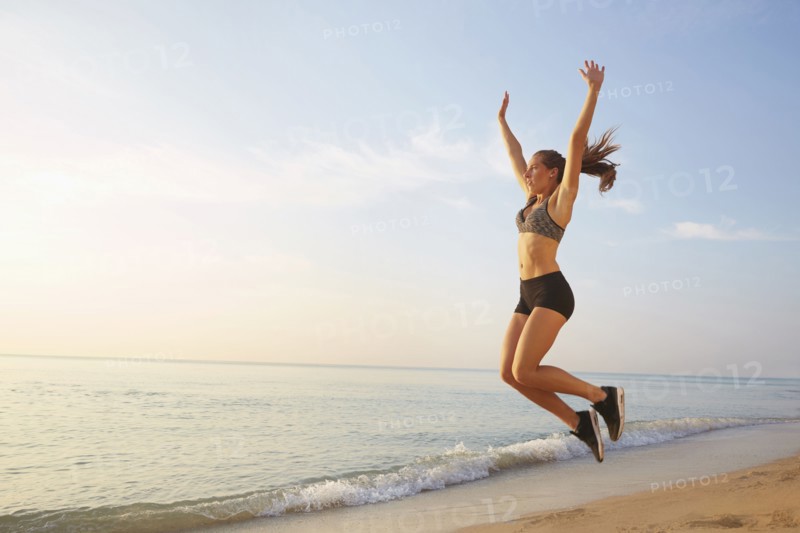 Athlete jumping for joy on beach