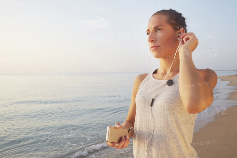 Athlete listening to earphones on beach
