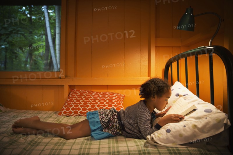 Mixed race girl reading on bed