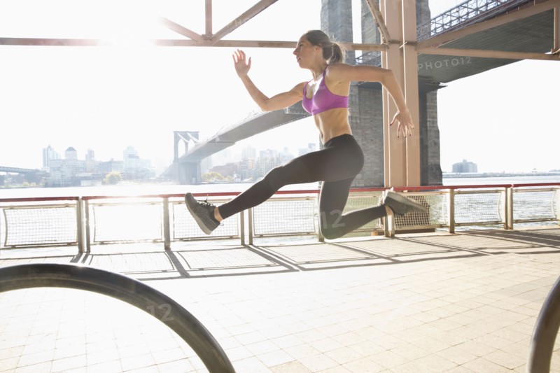 Caucasian runner jumping on waterfront