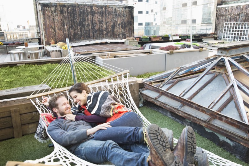 Couple laying in hammock on urban rooftop