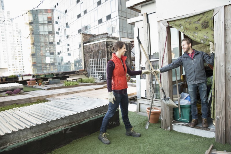 Couple holding gardening tools on urban rooftop
