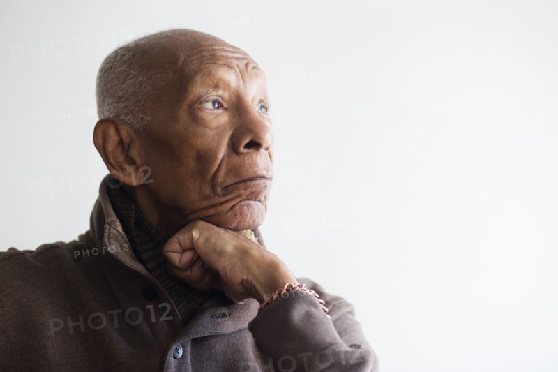 Older Black man resting chin in hand