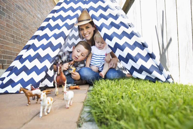 Caucasian mother and children in teepee playing with toy horses