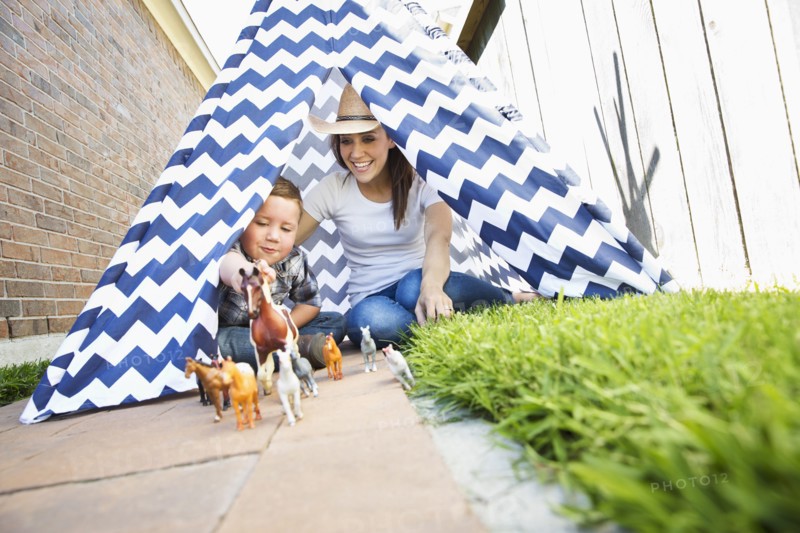 Caucasian mother and son in teepee playing with toy horses