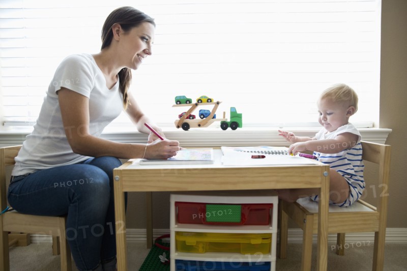 Caucasian mother and baby daughter using coloring books