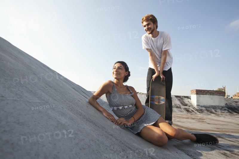 Mixed Race couple on rooftop with skateboard