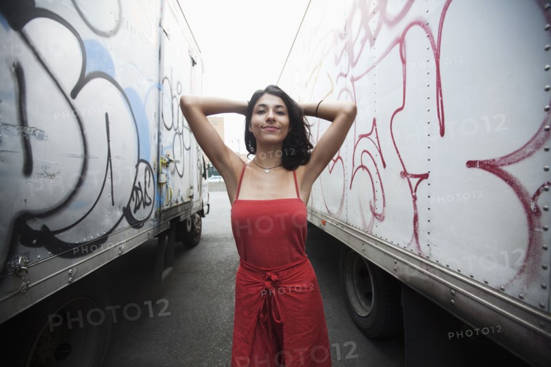 Mixed Race woman between semi-trucks with graffiti