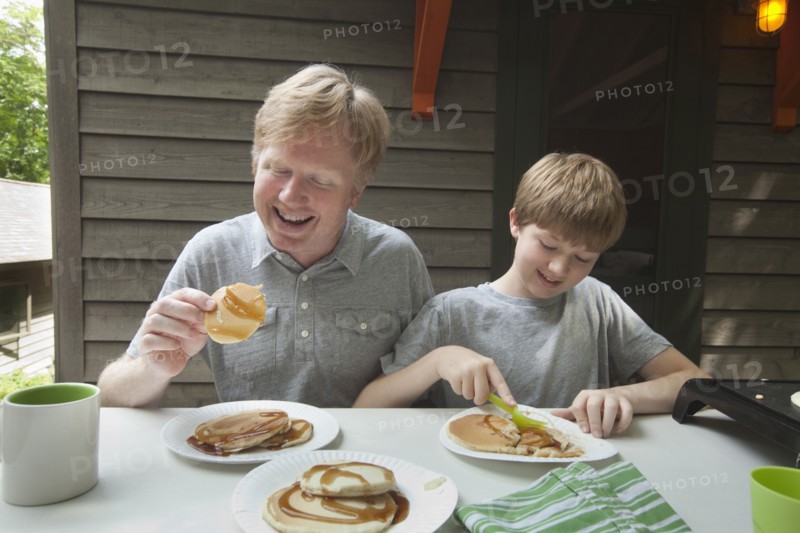 Caucasian father and son eating pancakes outdoors
