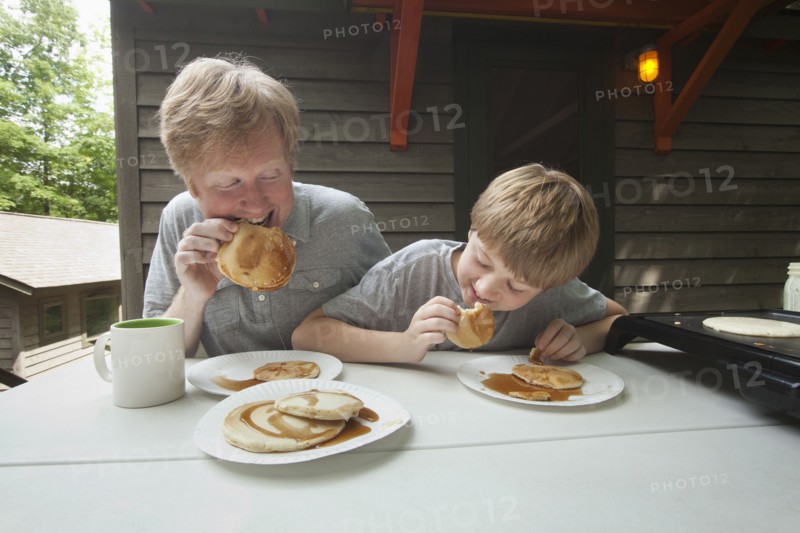 Caucasian father and son eating pancakes outdoors