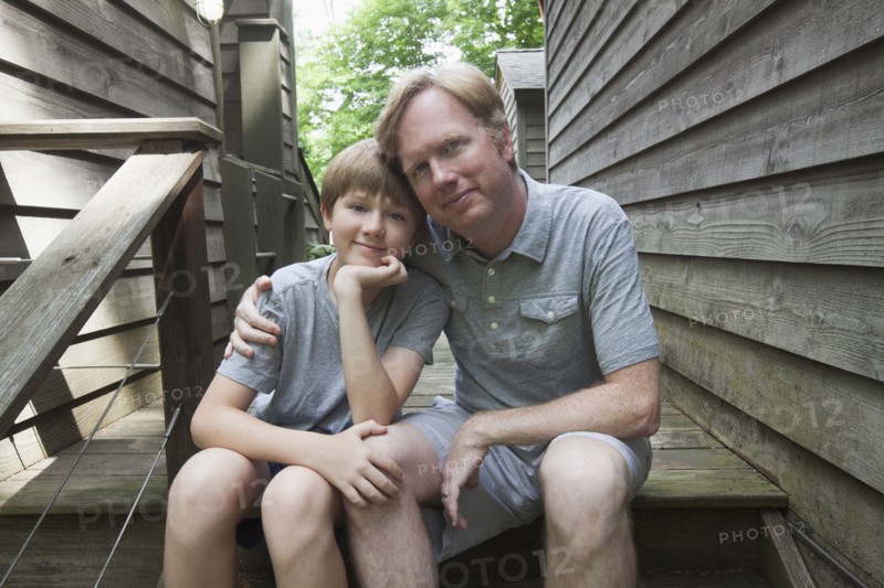 Caucasian father and son hugging on wooden staircase