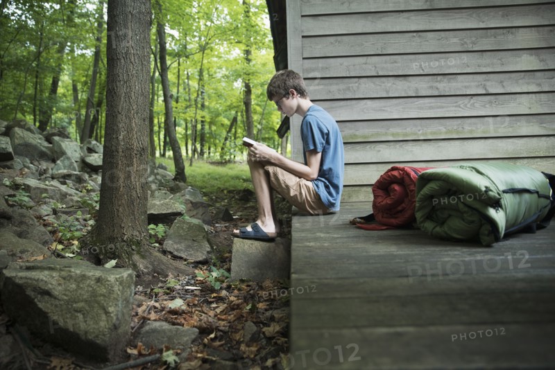 Caucasian boy reading book on wooden patio