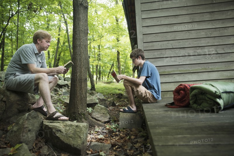 Caucasian father and son reading books at cabin