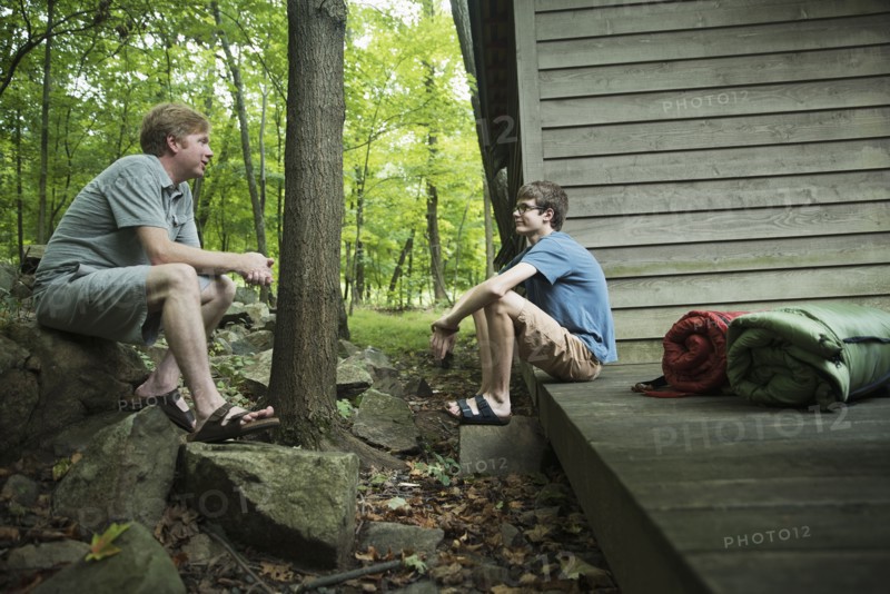 Caucasian father and son talking at cabin