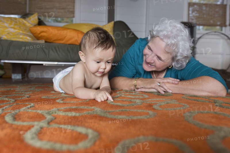 Grandmother and grandson laying on carpet