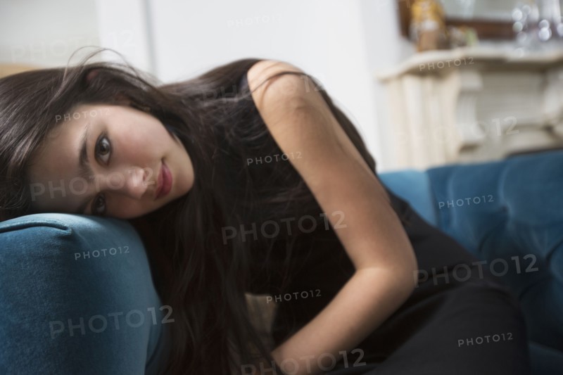 Pensive Caucasian girl resting head on armchair