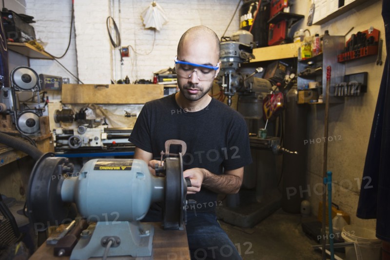 Mixed Race man using machinery in workshop