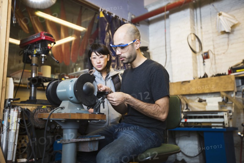 Man and woman using machinery in workshop