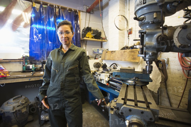 Mixed Race woman posing near machinery in workshop